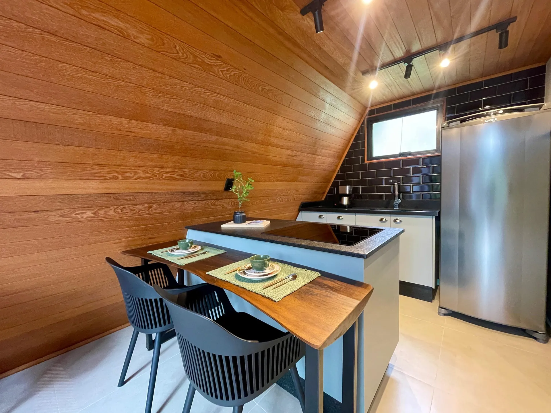 Cozinha com bancada, mesa para dois e geladeira inox