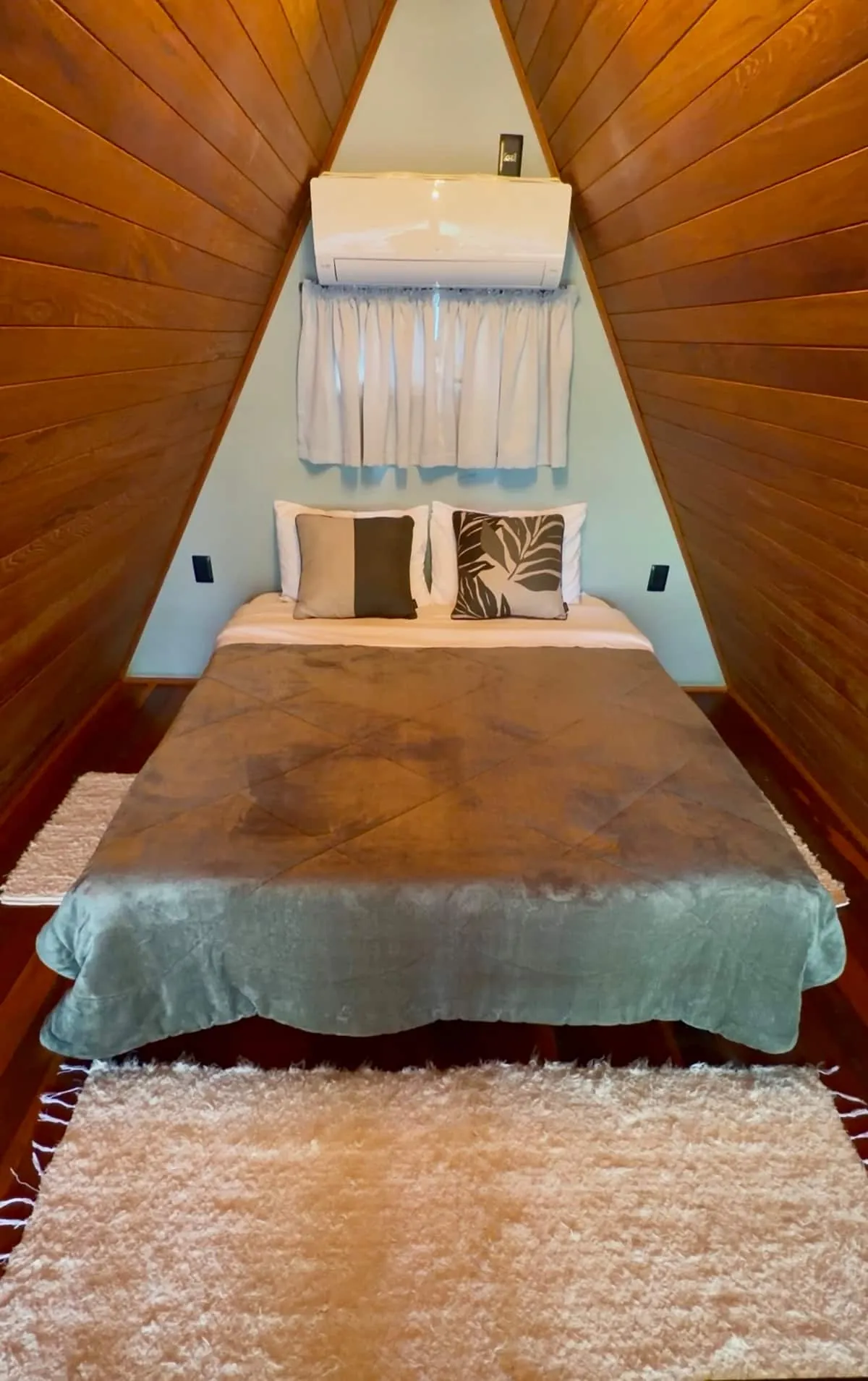 Cama de casal no mezanino, sob o telhado de madeira